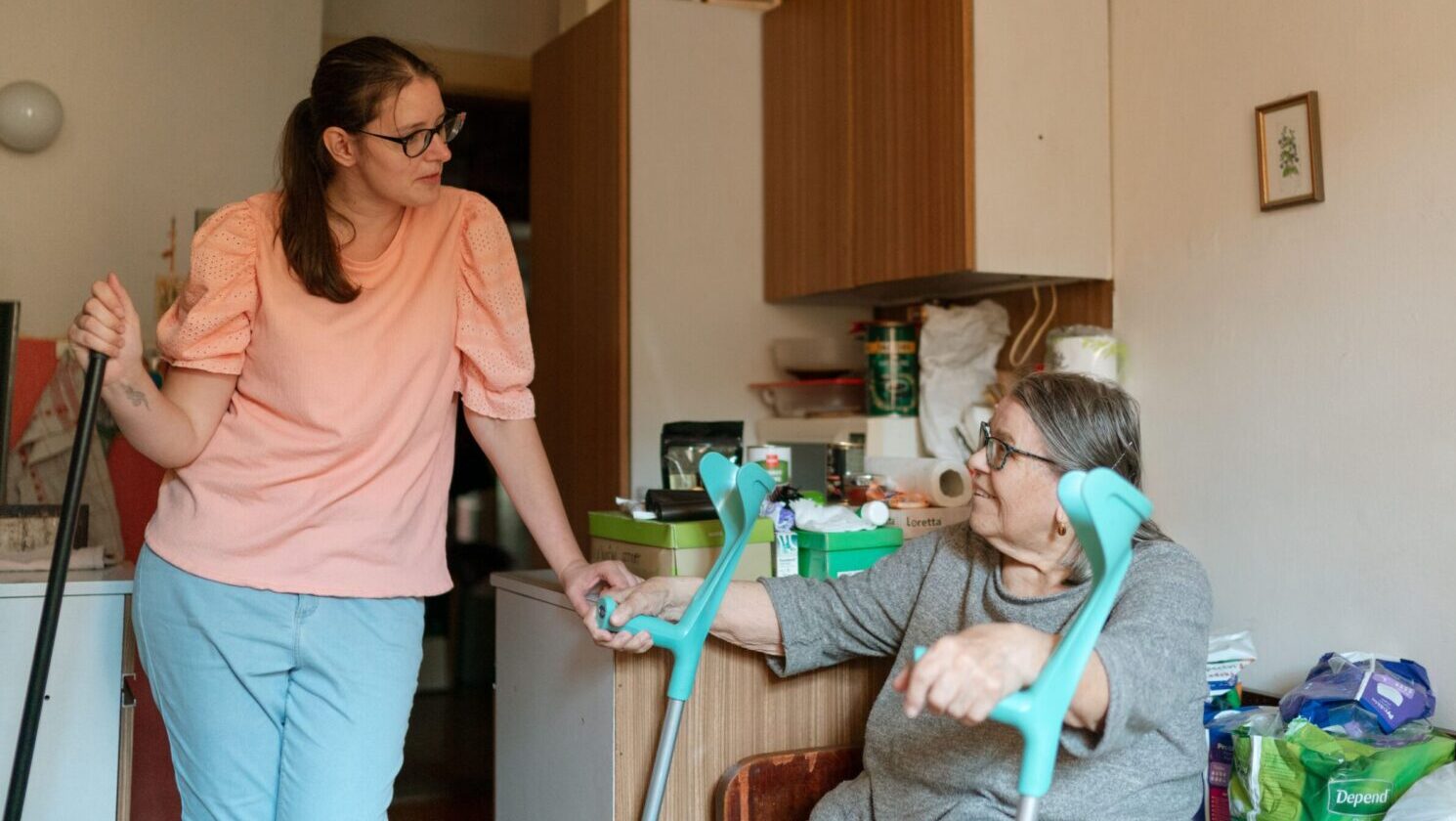A cheerful woman receives grocery bags from a delivery person at home.